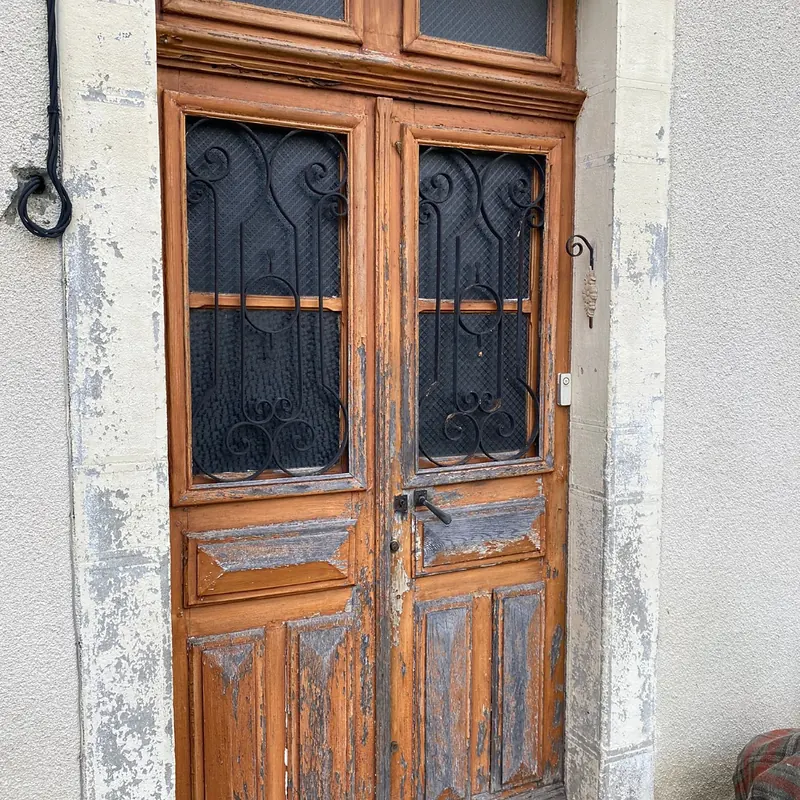 Avant : Ancienne porte d’entrée en bois à deux vantaux, peinture écaillée et grilles en fer forgé, avant son remplacement