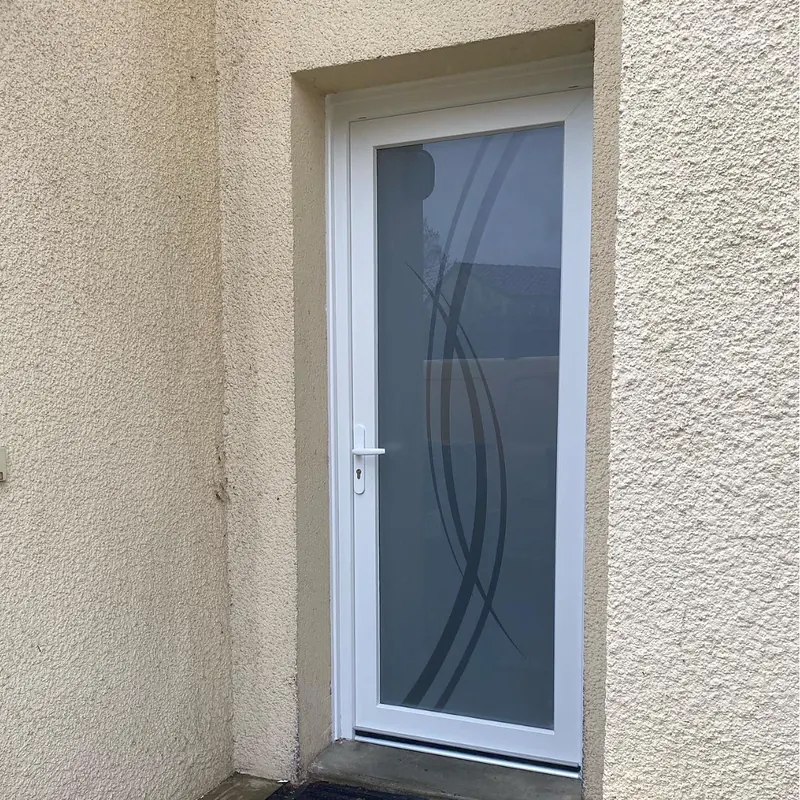 Après : Porte d’entrée PVC blanche avec vitrage dépoli à motif de courbes, sur une façade crépie